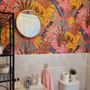 bathroom with bright wallpaper and gold statement mirror