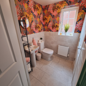 bathroom with bright wallpaper and gold statement mirror